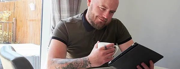 Man_with_tattoos_smiling_looking_at_tablet.jpg